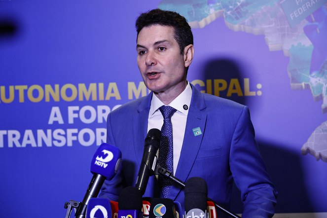 Homem falando ao microfone num evento. 